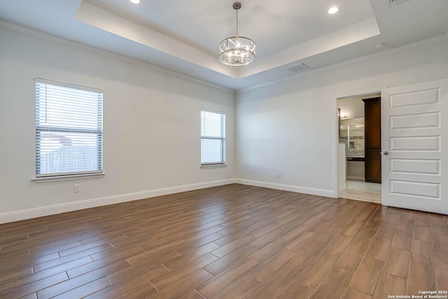 empty room featuring an inviting chandelier, a raised ceiling, and a healthy amount of sunlight