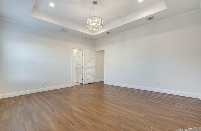 unfurnished room with a notable chandelier, a raised ceiling, and ornamental molding