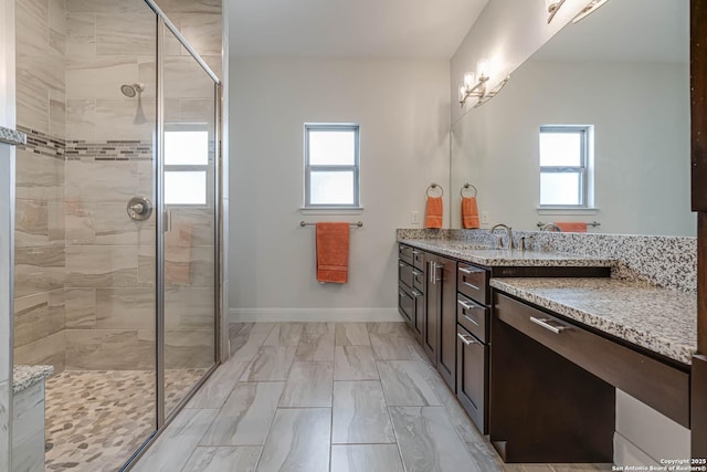 bathroom with plenty of natural light, a shower with door, and vanity