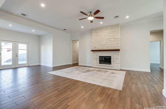 unfurnished living room featuring crown molding, a fireplace, ceiling fan, and french doors