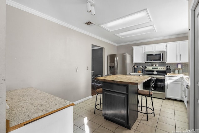 kitchen with a center island, butcher block counters, white cabinets, a breakfast bar, and stainless steel appliances