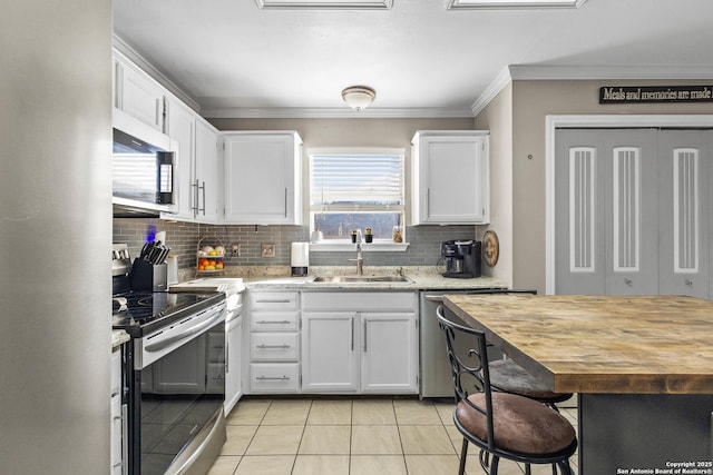 kitchen featuring sink, stainless steel appliances, white cabinets, and light tile patterned floors