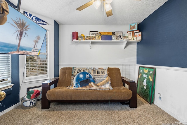 living area featuring ceiling fan, carpet flooring, and a textured ceiling