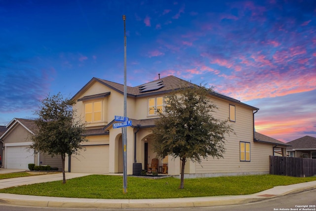 view of front of property featuring a garage, a yard, solar panels, and central air condition unit