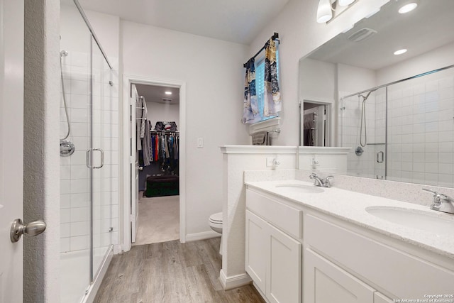 bathroom with hardwood / wood-style flooring, toilet, walk in shower, and vanity