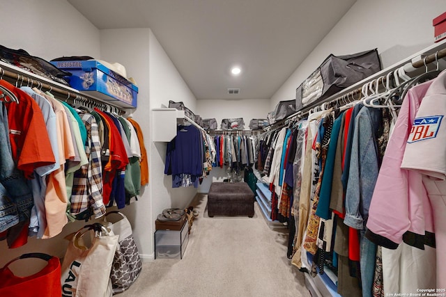 walk in closet with light carpet