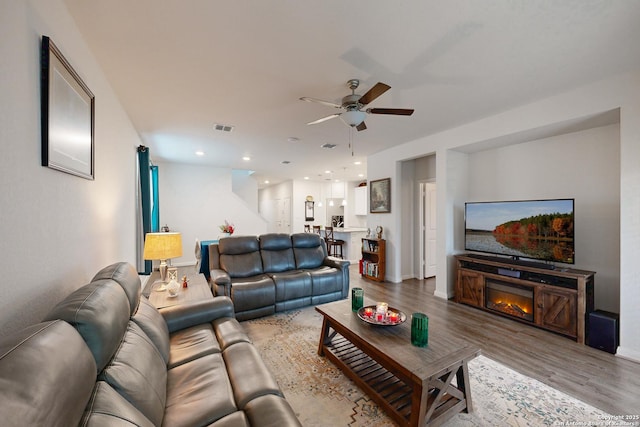 living room with hardwood / wood-style flooring, ceiling fan, and a fireplace