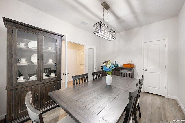 dining area featuring wood-type flooring and an inviting chandelier