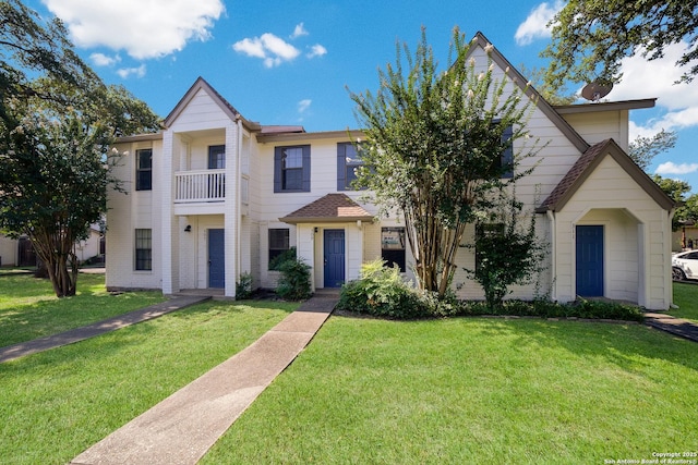 view of front of house with a balcony and a front lawn