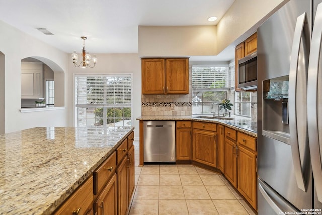 kitchen featuring decorative light fixtures, stainless steel appliances, sink, light stone counters, and light tile patterned floors