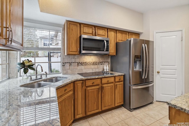 kitchen with light stone countertops, stainless steel appliances, sink, backsplash, and light tile patterned floors