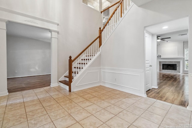 staircase with ornate columns, ceiling fan, and tile patterned floors