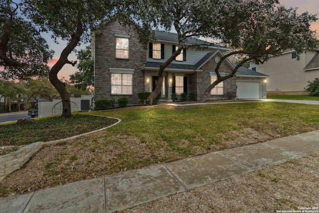 view of front of home with a yard, central AC unit, and a garage