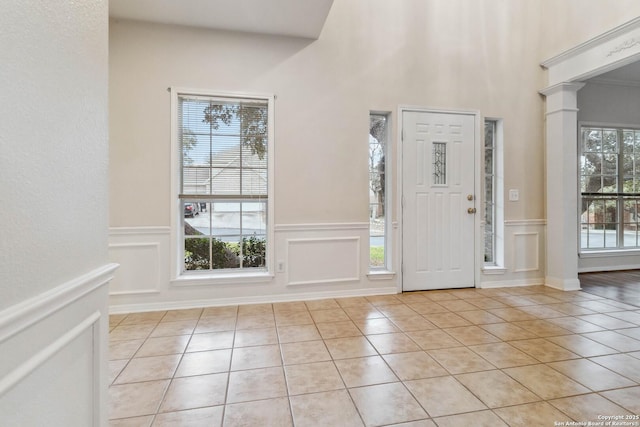 foyer featuring light tile patterned flooring and decorative columns