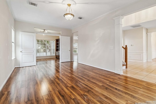 unfurnished room with decorative columns, ceiling fan, ornamental molding, and wood-type flooring