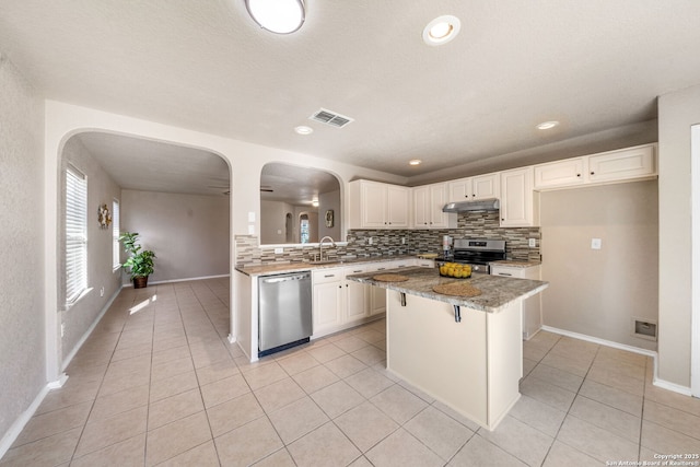 kitchen featuring light stone countertops, white cabinetry, appliances with stainless steel finishes, and a center island