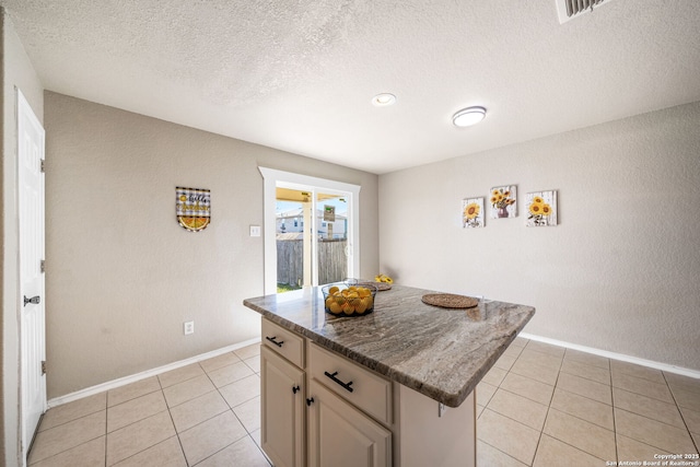 kitchen with a breakfast bar, a textured ceiling, light tile patterned floors, and a center island