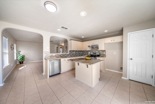 kitchen with tasteful backsplash, a kitchen island, stainless steel appliances, a breakfast bar area, and light tile patterned flooring