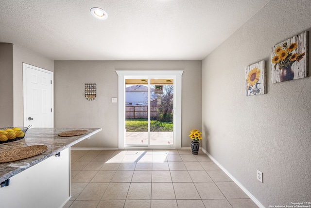 doorway to outside with light tile patterned floors and a textured ceiling