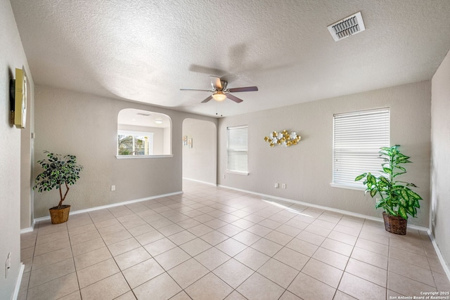 spare room with ceiling fan, a healthy amount of sunlight, light tile patterned floors, and a textured ceiling