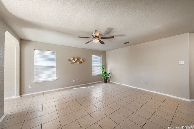 unfurnished room with a textured ceiling, light tile patterned floors, and ceiling fan