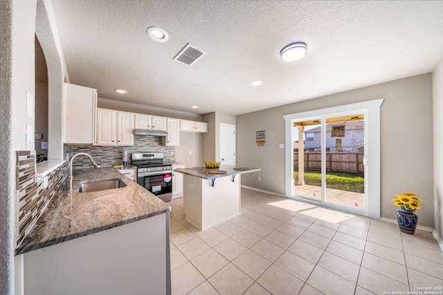 kitchen with stainless steel electric stove, sink, tasteful backsplash, light stone counters, and a kitchen bar