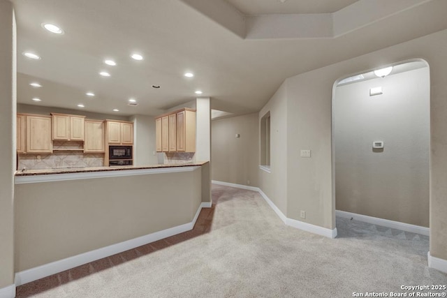 kitchen with black microwave, light brown cabinets, kitchen peninsula, and decorative backsplash