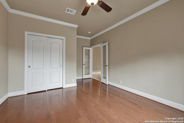 unfurnished bedroom with crown molding, hardwood / wood-style flooring, ceiling fan, french doors, and a closet