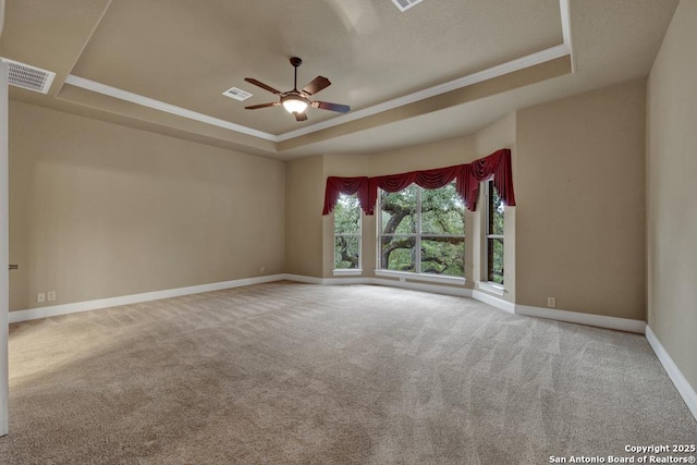 empty room with a raised ceiling, crown molding, carpet floors, and ceiling fan