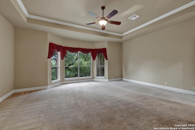 carpeted spare room with crown molding, ceiling fan, and a raised ceiling