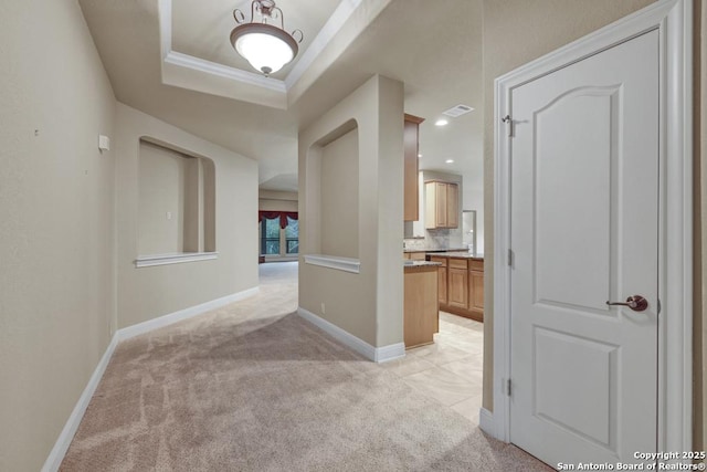 hall featuring crown molding, light colored carpet, and a tray ceiling