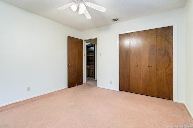 unfurnished bedroom with light colored carpet, a closet, and ceiling fan