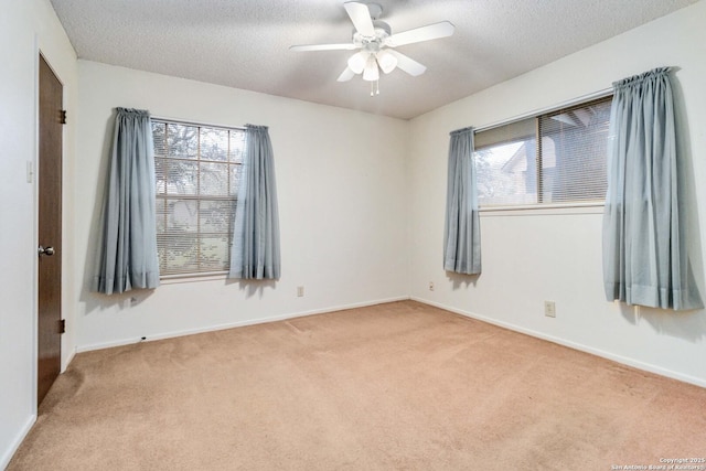 empty room featuring ceiling fan, light colored carpet, and a textured ceiling