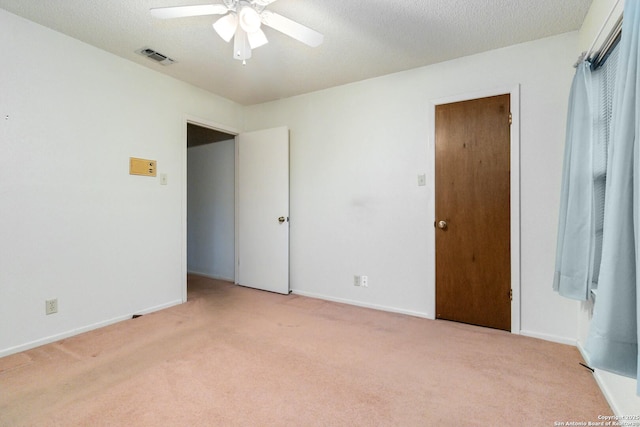 unfurnished room with light colored carpet, a textured ceiling, and ceiling fan