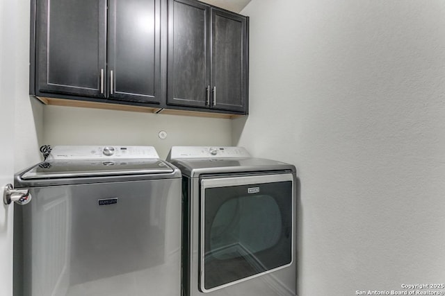 clothes washing area featuring cabinets and independent washer and dryer