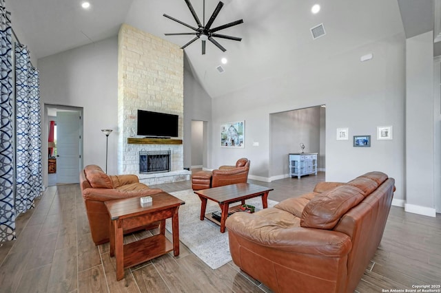 living room featuring ceiling fan, a fireplace, and high vaulted ceiling