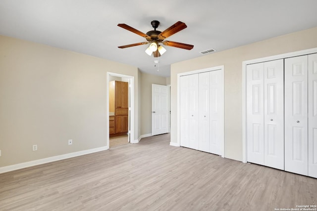 unfurnished bedroom featuring multiple closets, ceiling fan, ensuite bath, and light hardwood / wood-style flooring