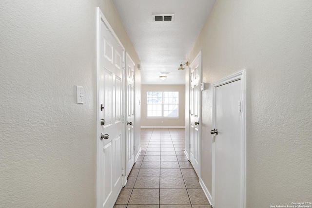 corridor with light tile patterned floors and a textured ceiling