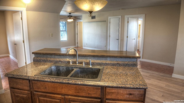 kitchen with an island with sink, sink, ceiling fan, and light hardwood / wood-style flooring