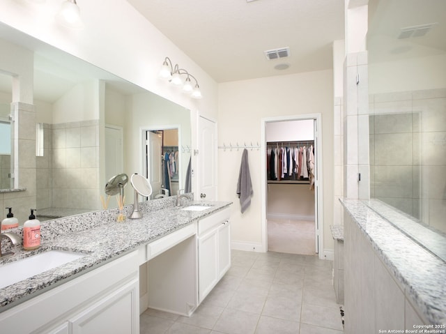 bathroom featuring tile patterned flooring, vanity, and tiled shower