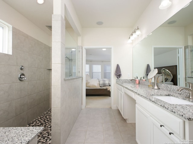 bathroom featuring tile patterned flooring, vanity, and tiled shower