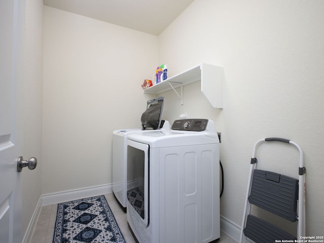 clothes washing area with light tile patterned floors and washer and clothes dryer