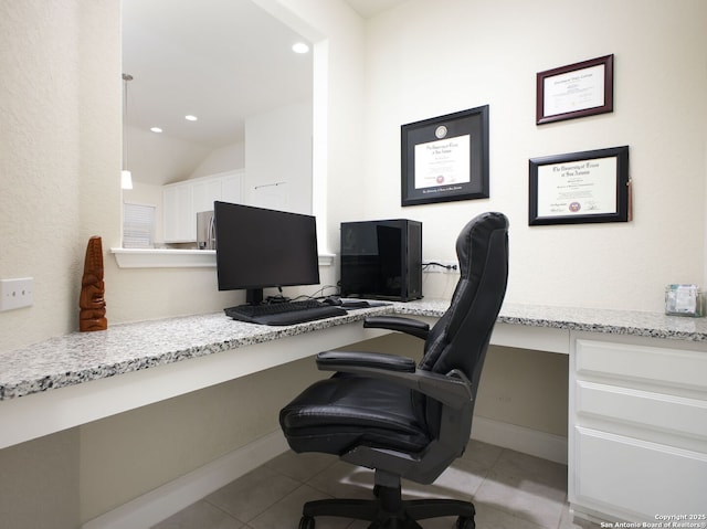 office space with lofted ceiling, built in desk, and light tile patterned floors