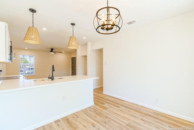 kitchen featuring white cabinetry, sink, pendant lighting, and range