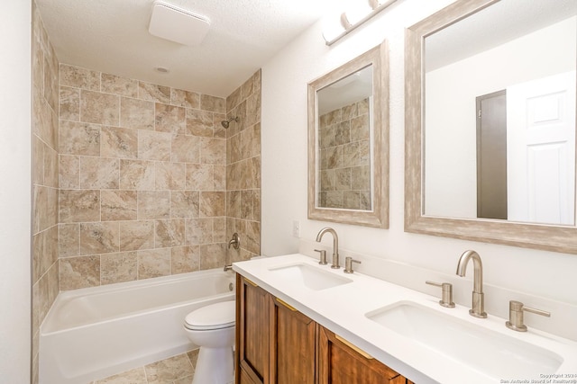 full bathroom with tiled shower / bath, vanity, toilet, and a textured ceiling