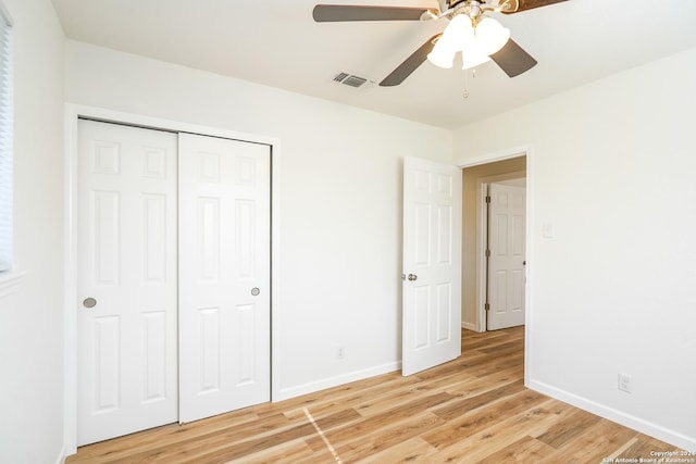 unfurnished bedroom with light wood-type flooring, ceiling fan, and a closet