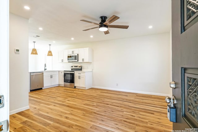 kitchen with sink, light hardwood / wood-style flooring, white cabinetry, stainless steel appliances, and decorative light fixtures