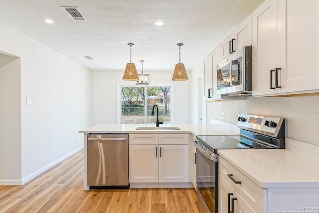 kitchen with white cabinetry, sink, pendant lighting, and appliances with stainless steel finishes