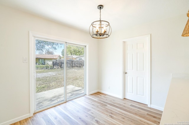 unfurnished dining area featuring an inviting chandelier and light hardwood / wood-style floors