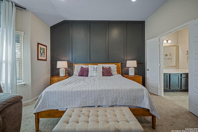 carpeted bedroom with multiple windows, lofted ceiling, and ensuite bath